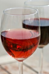 A glass of rosé wine in front of a glass of red wine outdoors in spring.