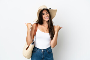 Young Brazilian woman with Pamela holding a beach bag isolated on white background with thumbs up gesture and smiling