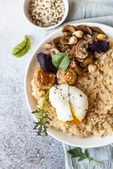 Savory porridge for breakfast. Oatmeal or spelt flakes with poached egg, fried mushrooms and herbs. Healthy food. Keto diet. Top view.