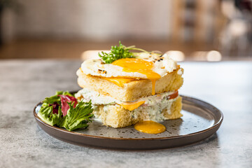Croque Madame - hot french sandwich with ham, melted cheese, fried egg and sauce with salad. Delicious breakfast.