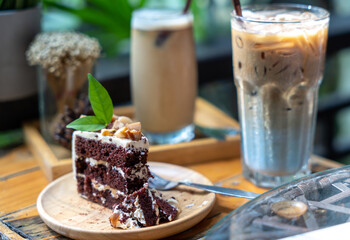 Selective focus, Slices of Homemade chocolate cake decorated with macadamia with iced coffee on dessert table at cafe, on nature background