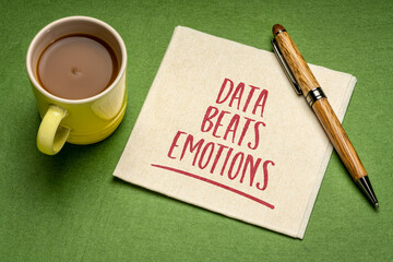 data beats emotion reminder, handwriting on a napkin with a cup of coffee, facts, research, science and analytics concept
