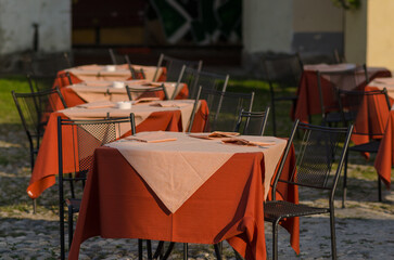 tables of an open-air restaurant in the square of a tourist place, a table well prepared with colored tablecloths, on holidays and holidays most tourists love to dine outdoors in the summer.