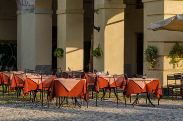 tables of an open-air restaurant in the square of a tourist place, a table well prepared with colored tablecloths, on holidays and holidays most tourists love to dine outdoors in the summer.