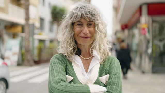 Middle age woman smiling confident standing with arms crossed gesture at street