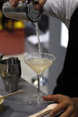 barman elaborando coctel con su coctelera y vertiendo el licor en copa de cristal