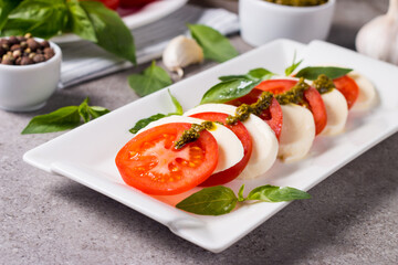 Close-up photo of caprese salad with ripe tomatoes, basil, buffalo mozzarella cheese. Italian and Mediterranean food concept. Fresh and healthy organic meal. Starter and antipasti. 