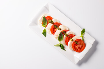 Close-up photo of caprese salad with ripe tomatoes, basil, buffalo mozzarella cheese. Italian and Mediterranean food concept. Fresh and healthy organic meal. Starter and antipasti. 