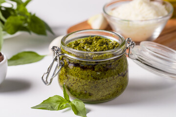 Basil pesto sauce in a jar. Ingredients for cooking, cheese, parmesan, garlic, olive oil. 