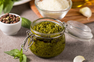 Basil pesto sauce in a jar. Ingredients for cooking, cheese, parmesan, garlic, olive oil. 