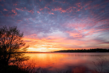 Fototapeta na wymiar Beautiful sunset, sky with clouds above lake with trees around.