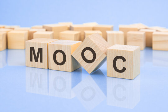 four wooden blocks with the letters MOOC on the bright surface of a pale lilac background. the inscription on the cubes is reflected from the surface. business concept.