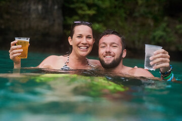 This is what real refreshment looks like. Portrait of a happy couple enjoying drinks while relaxing in the ocean.