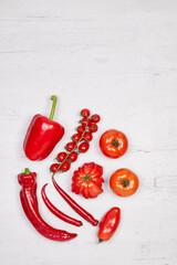grouped vegetables with red peppers, pepperoni and tomatoes on a wooden board