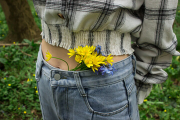 Bouquet of small yellow flowers on a woman's belt. First spring flowers. Early spring