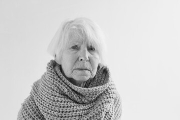 monochrome portrait of senior woman in scarf freezing cold at home. Health care, crisis, oldness concept