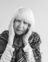 monochrome portrait of senior woman with headache in plaid. Health care, mature age, illness concept