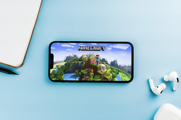 Fototapeta premium Minecraft mobile game app on the smartphone screen. Blue background with notepad and AirPods. Rio de Janeiro, RJ, Brazil. April 2022.