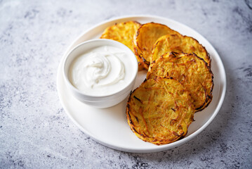 Potato hash browns with sour cream sauce in a plate