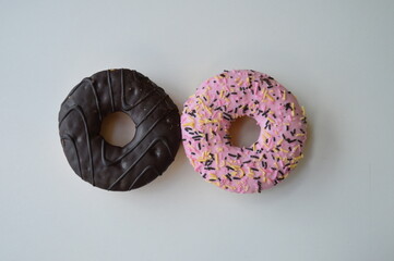 Colorful donuts with sprinkles, topped with chocolate and pink sugar topping on a white background