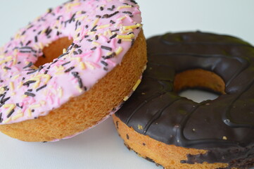 Colorful donuts with sprinkles, topped with chocolate and pink sugar topping on a white background
