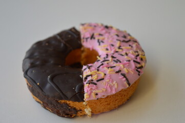Colorful donuts with sprinkles, topped with chocolate and pink sugar topping on a white background