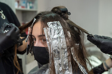 super cool stylist working on the image of a young girl in a beauty salon.