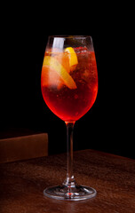 aperol spritz glass with sparkling ice on wooden table with dark background