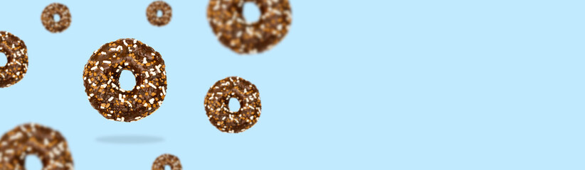 Glazed icing brown sweet sugar chocolate doughnut donut dessert on blue pastel background banner. Creative minimal blurred selective focus collage food mockup concept with copy space