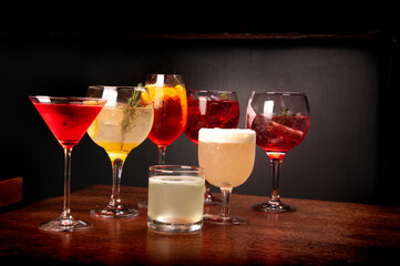 mixology collection of various assorted and colorful cocktails in front view wooden table and leather bench