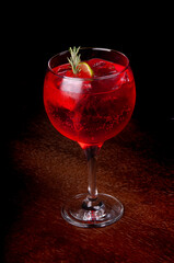 red cocktail glass with lemon rosemary gin and ice on wooden table