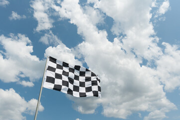 checkered flag on cloudy blue sky background