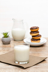 Mini donuts covered with chocolate glaze served with bottle, jug, glass of milk. Stack of tasty sweet sugar creamy or icing doughnuts dessert food on plate and napkin on kitchen. national donuts day