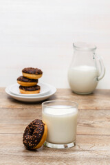 Mini donuts covered with chocolate glaze served with bottle, jug, glass of milk. Stack of tasty sweet sugar creamy or icing doughnuts dessert food on plate and napkin on kitchen. national donuts day