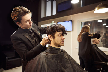 Salon. Man in a barber chair. The hairdresser serves the client in the barbershop. The concept of male cosmetology.