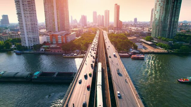 4K : Drones fly over the Chao Phraya River. Aerial view over bts skytrain, moving car on bridge, moving boat on river. view of downtown, Flying over Bangkok, Thailand.

