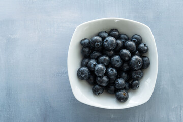 Delicious, tasty blueberries on a rustic background. Still life food photography. Blank space left around the berries for your text.