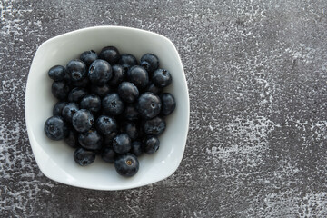 Delicious, tasty blueberries on a rustic background. Still life food photography. Blank space left around the berries for your text.