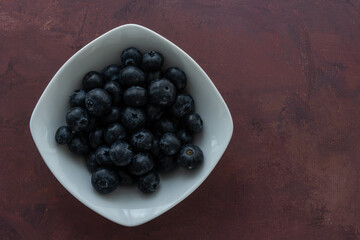 Delicious, tasty blueberries on a rustic background. Still life food photography. Blank space left around the berries for your text.