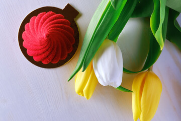 Red, bright dessert with yellow tulips on a white background top view