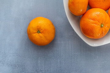 Delicious, tasty clementines lying on a rustic background. Still life food photography. Blank space left around the clementines for your text.