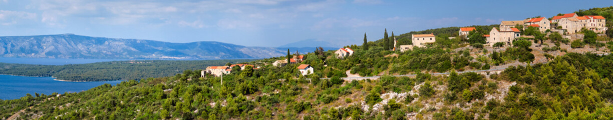 Fototapeta na wymiar Panoramic banner image of Hvar island in Croatia. Aerial view on mountains and coastline with blue water. Bird view panoramic image taken from old mountain road to Hvar.