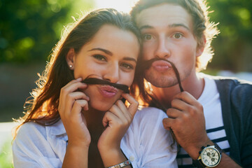 Obraz premium We moustache you if you notice anything different about us. Portrait of a young couple enjoying a silly moment together while bonding outdoors.