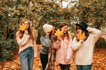 Four close female friends company group spending time together, talking, fooling around, hiding face, autumn. Outdoor