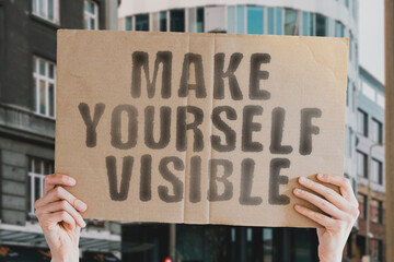 The phrase " Make yourself visible " on a banner in men's hands with blurred background. Share. Skill. Story. Storytelling. Strategy. Career. School. Procedure. Telling. Thinking. Vision. Plan. Future