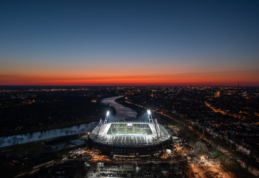 Bremen, Germany - March 2022: Aerial sunset cityscape over illuminated Weserstadion, home stadium of 2. Bundesliga football club SV Werder Bremen.