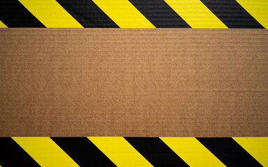 Cardboard background with a frame of forbidding yellow tape.Sticky tape in black with yellow color.A clean place for the warning text.