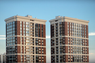 Two skyscrapers against the blue sky. The twin towers are made of red brick. New buildings. Sale of real estate. Buying apartments in a multi-storey building. © Svetliy