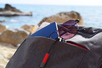 glasses and passport in a backpack on the beach