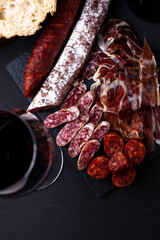 Spanish snack with chorizo, salchichon, jamon, fresh baguette and a glass of red wine.